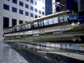 Straßenbahn mit Marmorlock schwebt über glänzender Marmorfläche in Hochhausumgebung. Photoshop-Kunst der Neunziger.