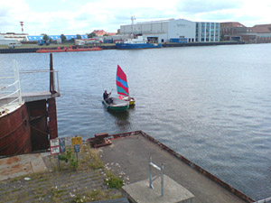 Optimist und Stahlboot im Hafenbecken